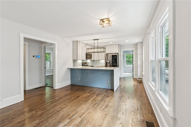 kitchen featuring a wealth of natural light, light countertops, a peninsula, and appliances with stainless steel finishes
