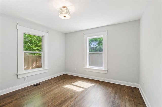 unfurnished room with visible vents, wood finished floors, and baseboards
