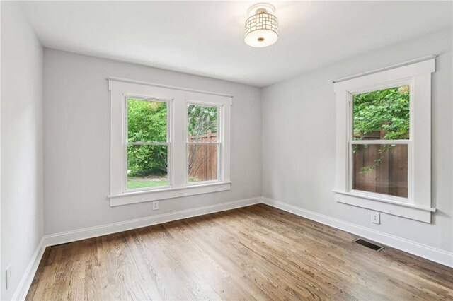 unfurnished room featuring baseboards, visible vents, and wood finished floors