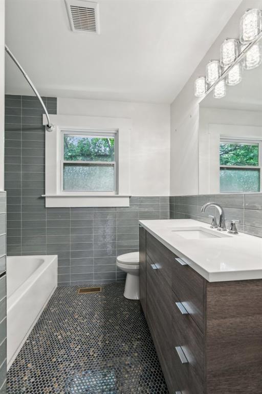 full bath with tile walls, toilet, vanity, visible vents, and tile patterned floors