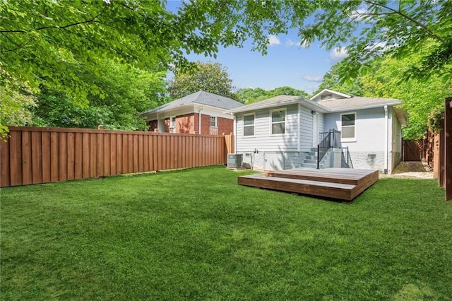 rear view of house featuring a wooden deck, a lawn, and a fenced backyard