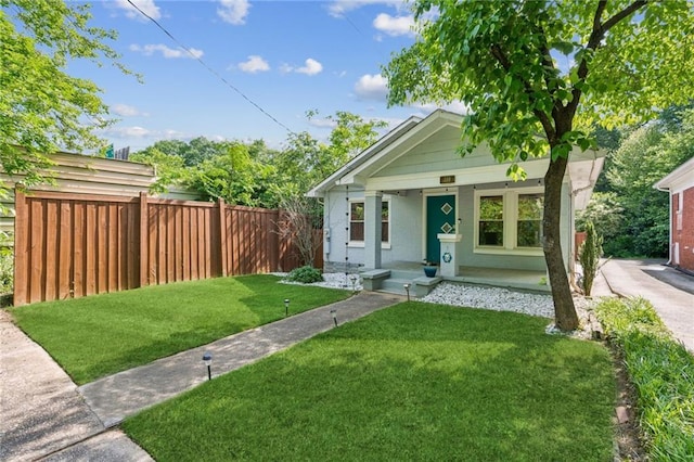 bungalow-style house with a front yard, brick siding, covered porch, and fence