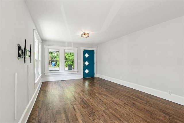 empty room with baseboards and dark wood-type flooring