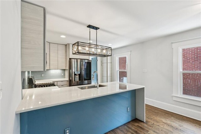 kitchen with baseboards, dark wood-style flooring, a sink, a peninsula, and stainless steel refrigerator with ice dispenser