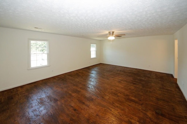 spare room featuring a wealth of natural light, dark wood-type flooring, and a textured ceiling