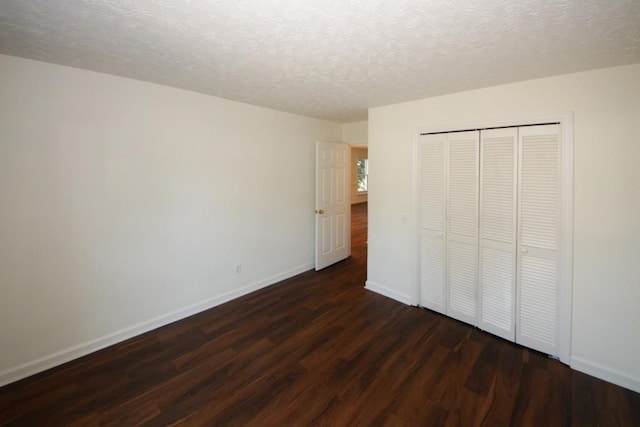 unfurnished bedroom with a textured ceiling, dark wood-type flooring, and a closet