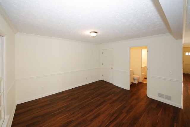 empty room with ornamental molding, a textured ceiling, and dark wood-type flooring