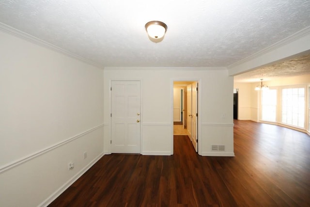 spare room featuring a chandelier, ornamental molding, a textured ceiling, and dark wood-type flooring