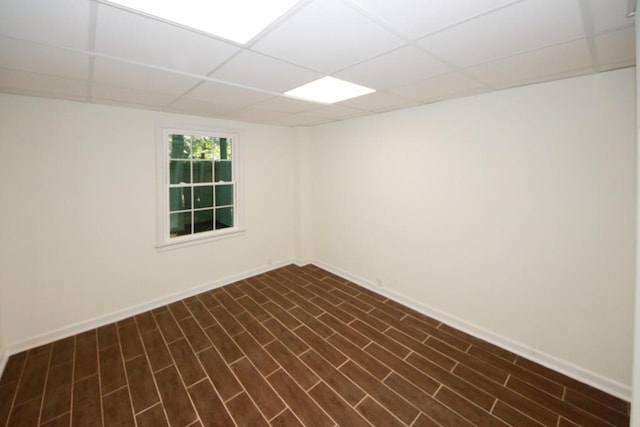 unfurnished room with a drop ceiling and dark wood-type flooring