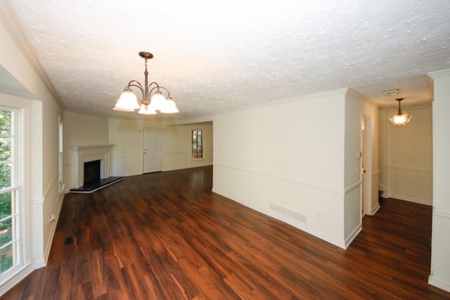 unfurnished living room with dark hardwood / wood-style flooring, a textured ceiling, and a notable chandelier