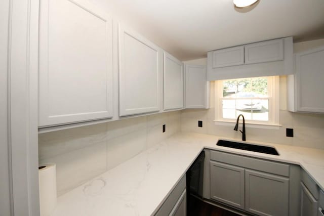 kitchen with light stone countertops, gray cabinets, tasteful backsplash, and sink