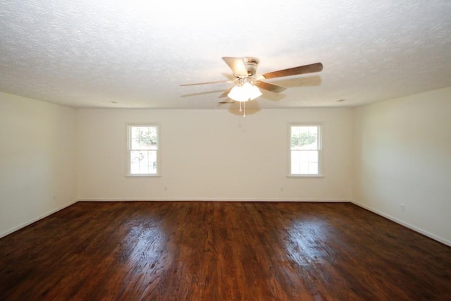 empty room with a textured ceiling, dark wood-type flooring, and a healthy amount of sunlight