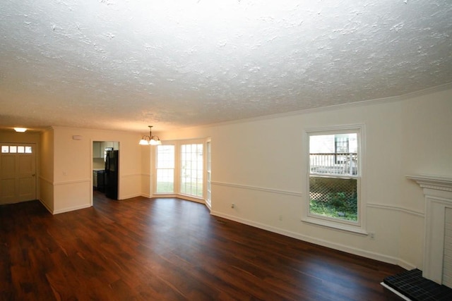 unfurnished living room featuring a wealth of natural light, crown molding, dark hardwood / wood-style floors, and a notable chandelier