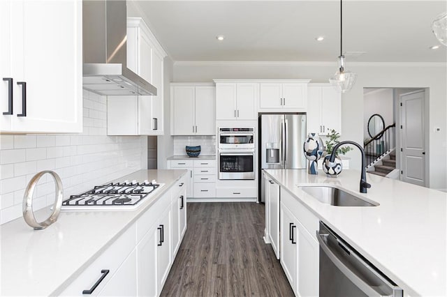 kitchen featuring wall chimney exhaust hood, sink, hanging light fixtures, stainless steel appliances, and white cabinets