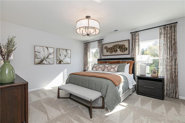 bedroom featuring light colored carpet and a notable chandelier