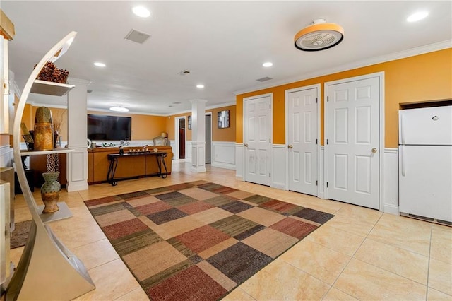 foyer entrance featuring crown molding, recessed lighting, ornate columns, light tile patterned floors, and a wainscoted wall