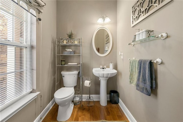bathroom with baseboards, wood finished floors, toilet, and a sink