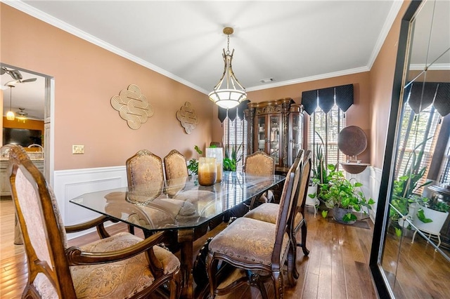 dining area featuring a wainscoted wall, ornamental molding, hardwood / wood-style flooring, and visible vents