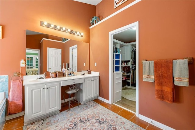 full bath with tile patterned flooring, baseboards, a sink, ensuite bath, and double vanity
