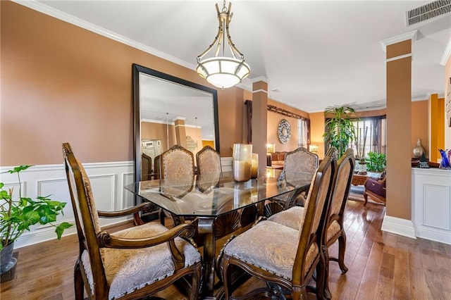 dining room with decorative columns, wainscoting, visible vents, ornamental molding, and hardwood / wood-style floors