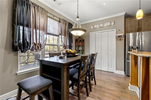 dining space with light wood-style flooring, crown molding, baseboards, and visible vents