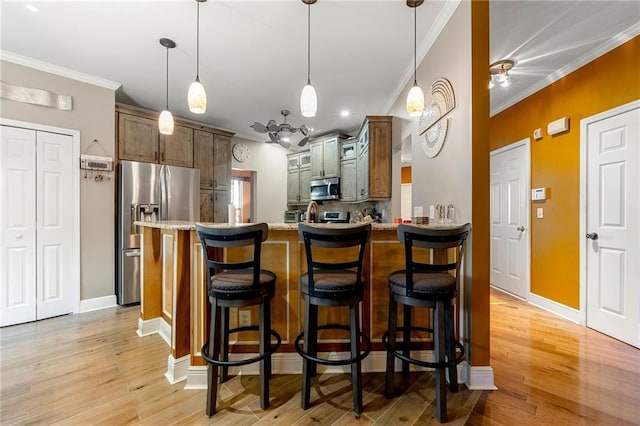 kitchen featuring light wood-type flooring, a peninsula, appliances with stainless steel finishes, and crown molding