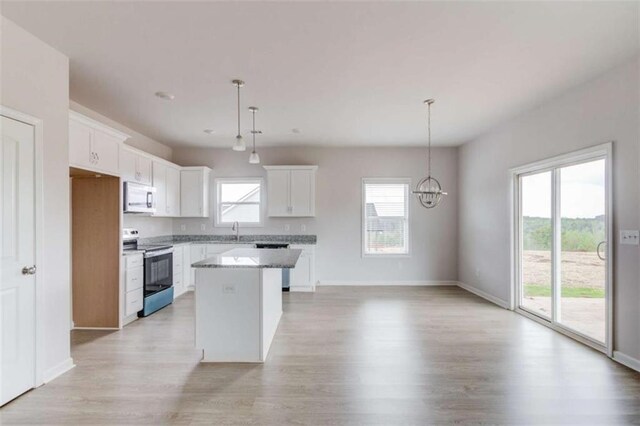 kitchen with a center island, stainless steel appliances, white cabinetry, and hanging light fixtures