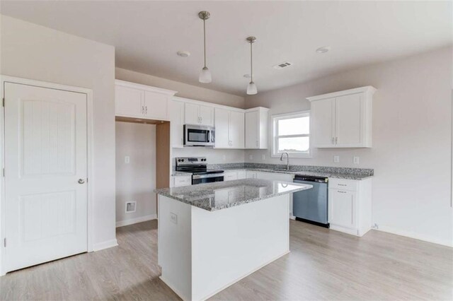 kitchen with appliances with stainless steel finishes, a kitchen island, stone countertops, white cabinetry, and hanging light fixtures