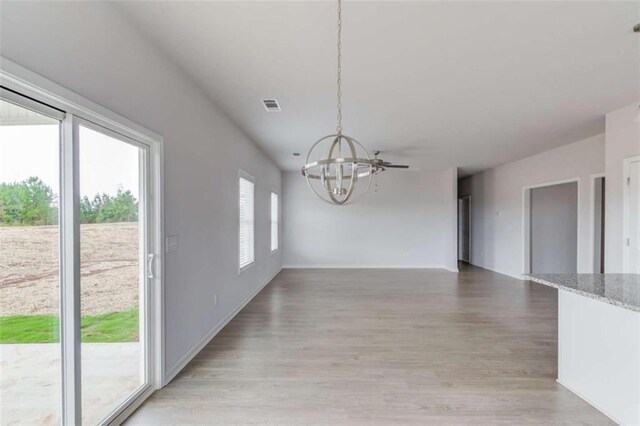 unfurnished dining area featuring light hardwood / wood-style floors and an inviting chandelier