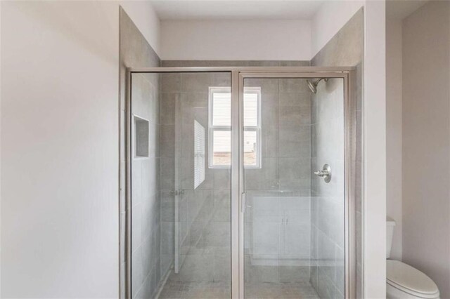 bathroom featuring toilet and a shower with door