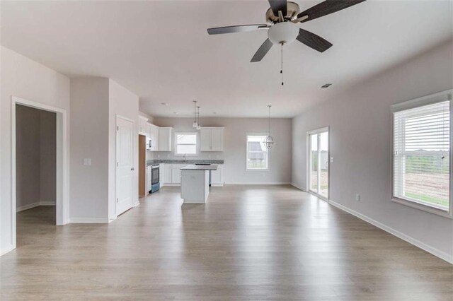 unfurnished living room featuring ceiling fan, plenty of natural light, and light hardwood / wood-style flooring