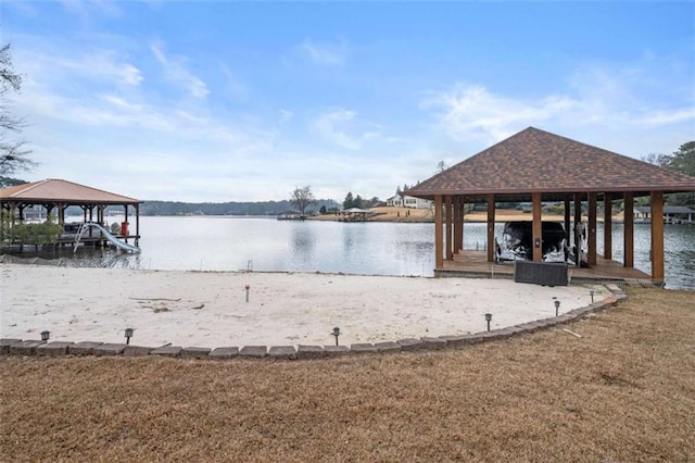 view of dock with a gazebo, a lawn, and a water view