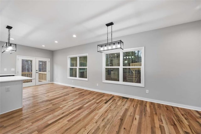 unfurnished dining area featuring light wood-style floors, recessed lighting, baseboards, and french doors