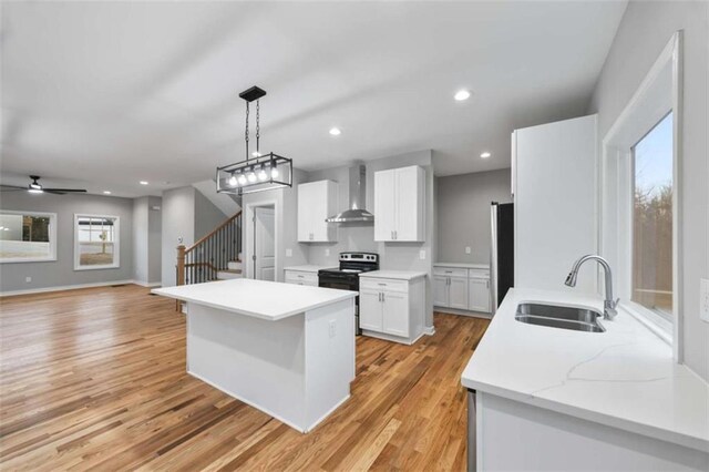 kitchen with a sink, light countertops, wall chimney range hood, fridge, and stainless steel electric stove