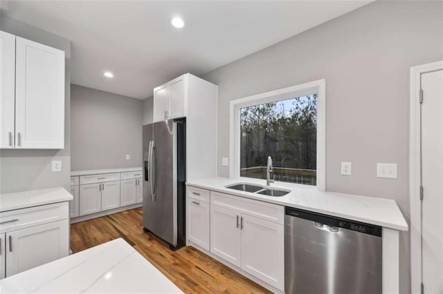 kitchen with recessed lighting, a sink, white cabinets, appliances with stainless steel finishes, and light wood finished floors