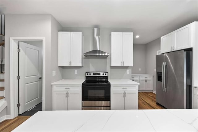 kitchen with wall chimney range hood, appliances with stainless steel finishes, white cabinets, and light countertops