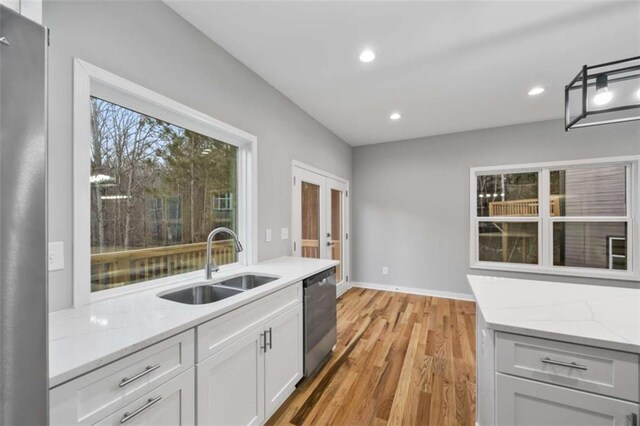 kitchen featuring light wood-style flooring, recessed lighting, a sink, light stone countertops, and dishwasher