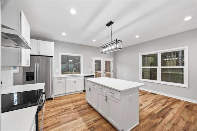 kitchen with light wood-style flooring, light countertops, stainless steel appliances, french doors, and a sink