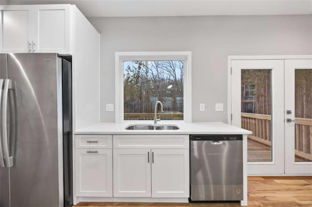 kitchen with appliances with stainless steel finishes, light countertops, french doors, white cabinetry, and a sink