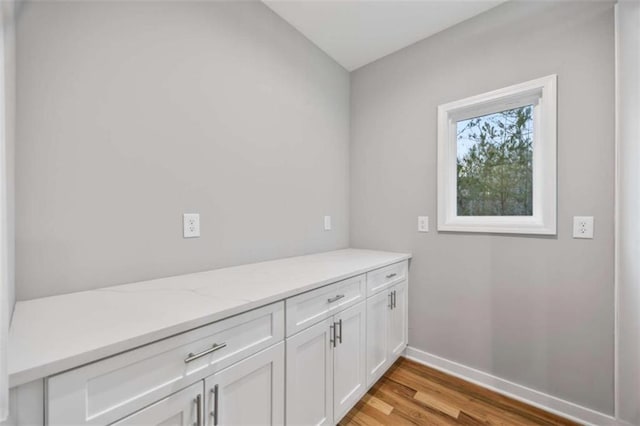 laundry room featuring light wood finished floors and baseboards