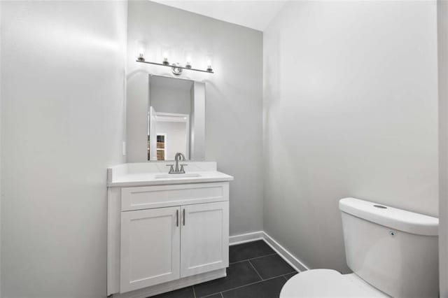 bathroom featuring toilet, tile patterned flooring, baseboards, and vanity