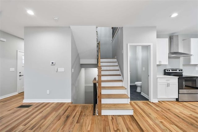 staircase featuring baseboards, wood finished floors, visible vents, and recessed lighting