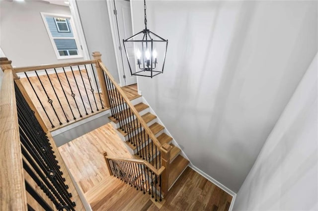 stairway featuring a chandelier and wood finished floors