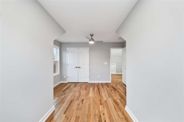 interior space featuring light wood finished floors, a closet, a ceiling fan, and baseboards