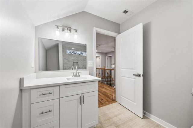 full bathroom with baseboards, visible vents, wood finished floors, vaulted ceiling, and vanity