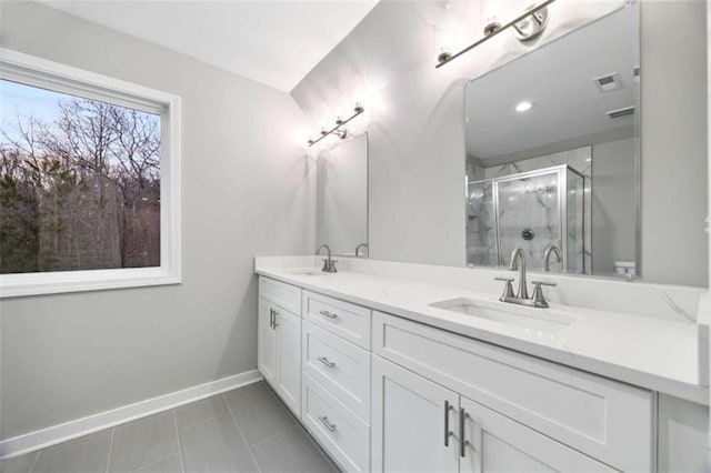 bathroom with double vanity, a stall shower, baseboards, visible vents, and a sink