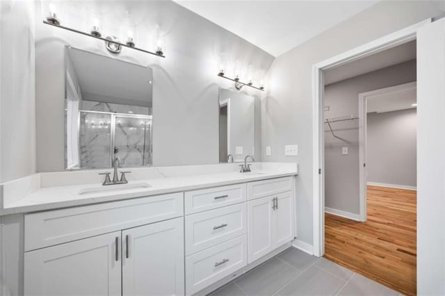 bathroom featuring double vanity, a stall shower, a sink, and tile patterned floors