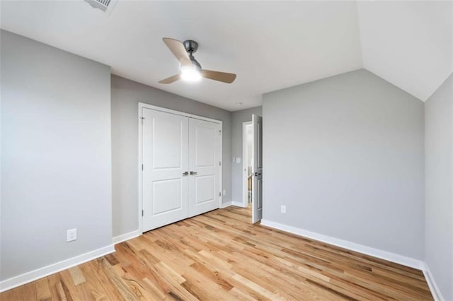 unfurnished bedroom featuring vaulted ceiling, light wood-type flooring, a ceiling fan, and baseboards