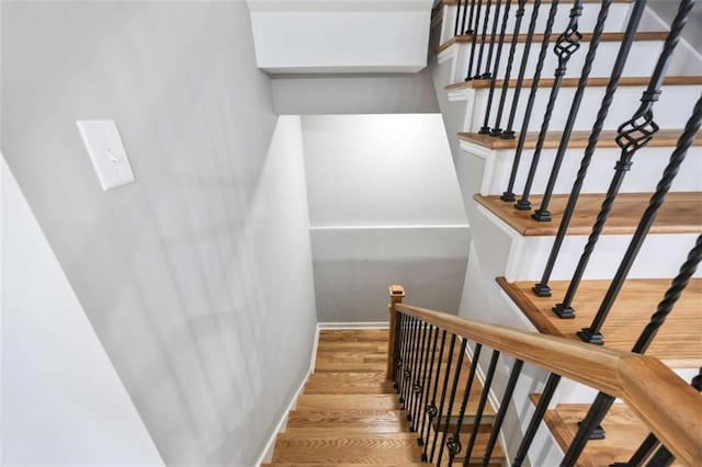 staircase featuring a skylight, wood finished floors, and baseboards