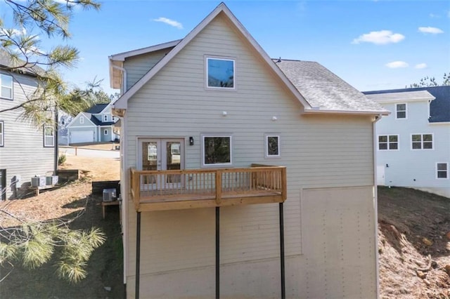 back of property with roof with shingles and a deck